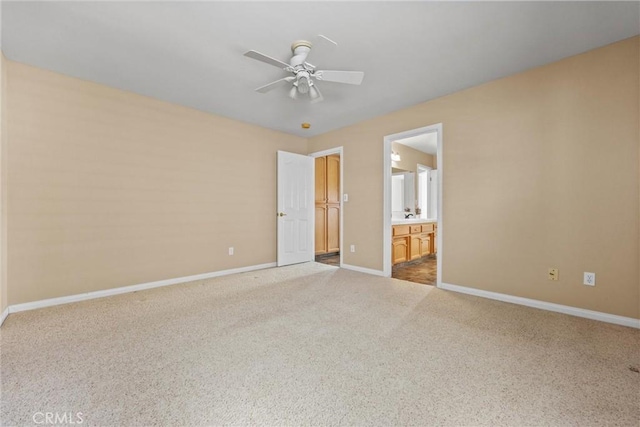 unfurnished bedroom with ensuite bathroom, ceiling fan, carpet flooring, and baseboards