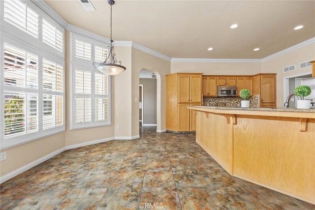 kitchen with visible vents, arched walkways, stainless steel microwave, a breakfast bar, and backsplash