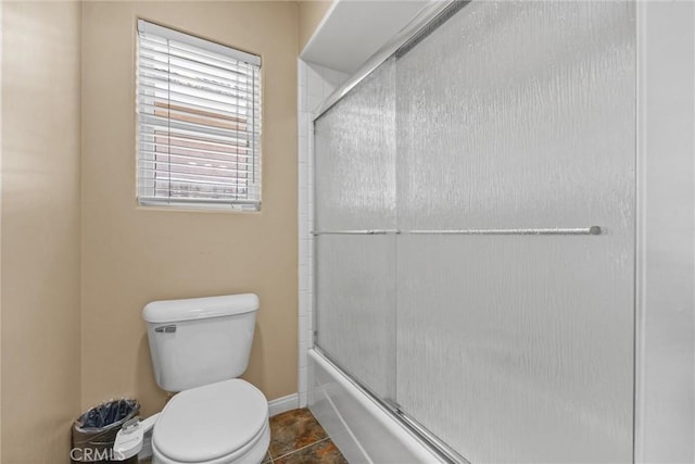 full bath with toilet, shower / bath combination with glass door, tile patterned flooring, and baseboards