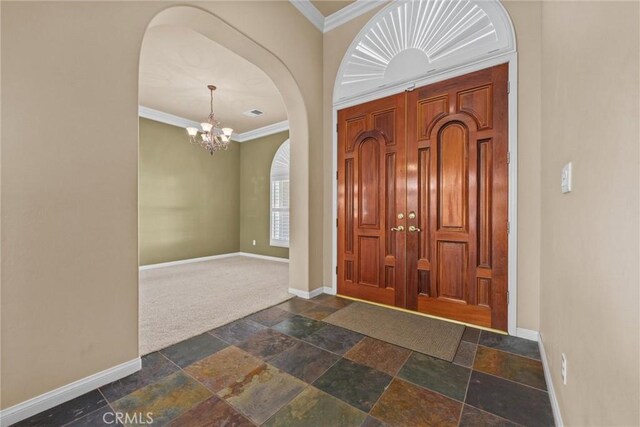 entrance foyer featuring crown molding, arched walkways, stone tile flooring, and baseboards