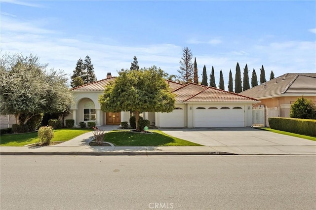 mediterranean / spanish-style house featuring concrete driveway, a tiled roof, an attached garage, fence, and stucco siding