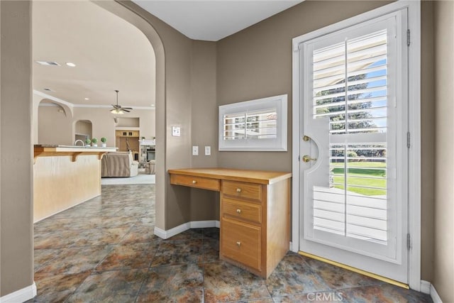 home office featuring arched walkways, ceiling fan, and baseboards