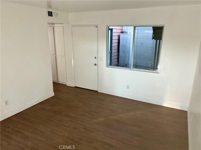 empty room featuring baseboards, visible vents, and wood finished floors