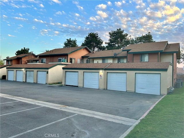 townhome / multi-family property featuring a garage, cooling unit, and stucco siding