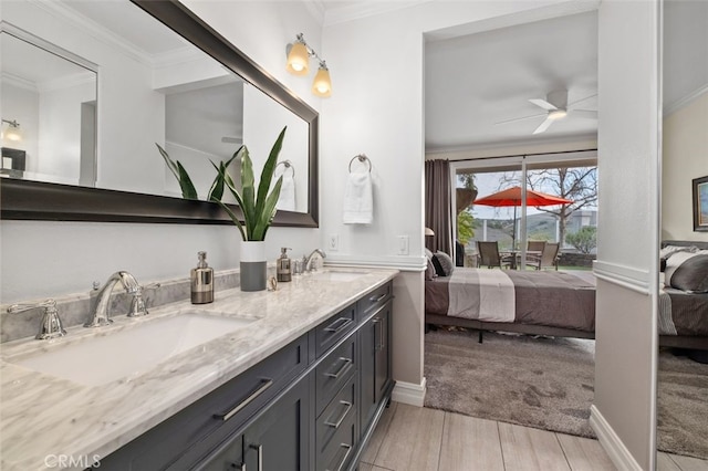 ensuite bathroom featuring a sink, ornamental molding, wood finished floors, and connected bathroom