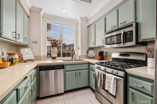 kitchen with green cabinetry, ornamental molding, stainless steel appliances, light countertops, and a sink