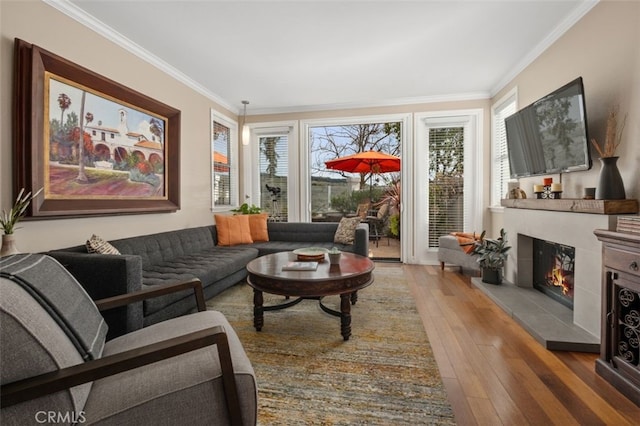 interior space with ornamental molding, a glass covered fireplace, and hardwood / wood-style flooring