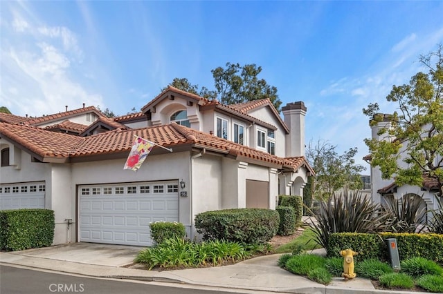 view of front facade with a chimney, stucco siding, concrete driveway, a garage, and a tiled roof