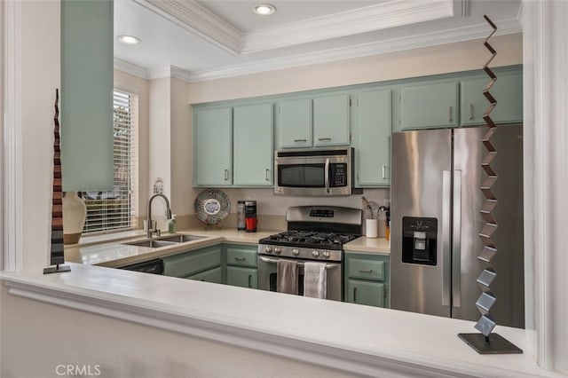 kitchen with a sink, light countertops, ornamental molding, appliances with stainless steel finishes, and green cabinetry