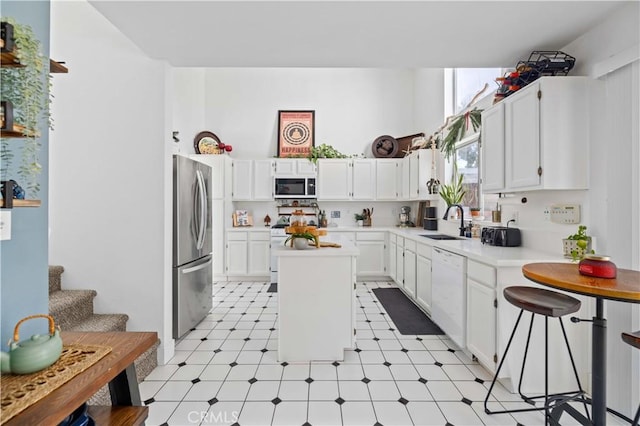 kitchen with a kitchen island, white appliances, light countertops, and a sink