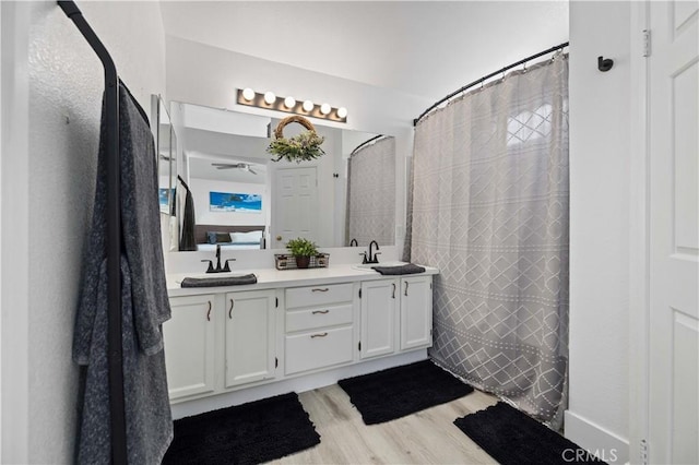 full bath featuring double vanity, curtained shower, a sink, and wood finished floors