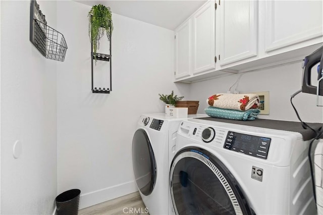 laundry area featuring light wood-style flooring, independent washer and dryer, cabinet space, and baseboards