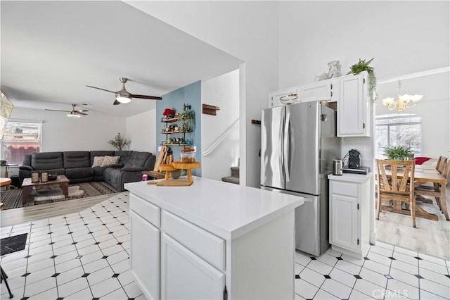 kitchen featuring ceiling fan with notable chandelier, light countertops, freestanding refrigerator, and white cabinets