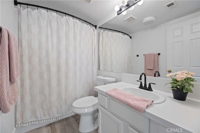 bathroom featuring toilet, visible vents, wood finished floors, and vanity