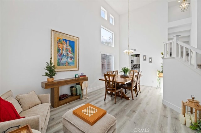 dining area with a chandelier, light wood-style floors, baseboards, and stairs