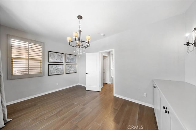 unfurnished dining area featuring baseboards, a chandelier, and wood finished floors