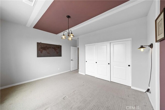 unfurnished bedroom with carpet, visible vents, a notable chandelier, and baseboards