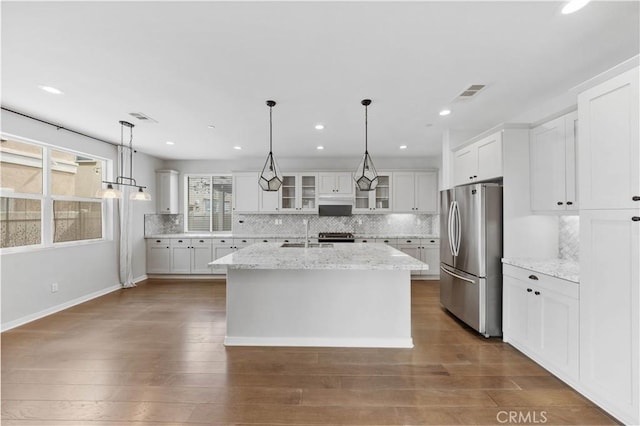 kitchen featuring dark wood-style flooring, a sink, visible vents, white cabinets, and freestanding refrigerator