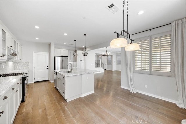 kitchen featuring stainless steel appliances, light wood-style flooring, backsplash, and visible vents