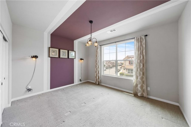 carpeted spare room with a chandelier, visible vents, and baseboards