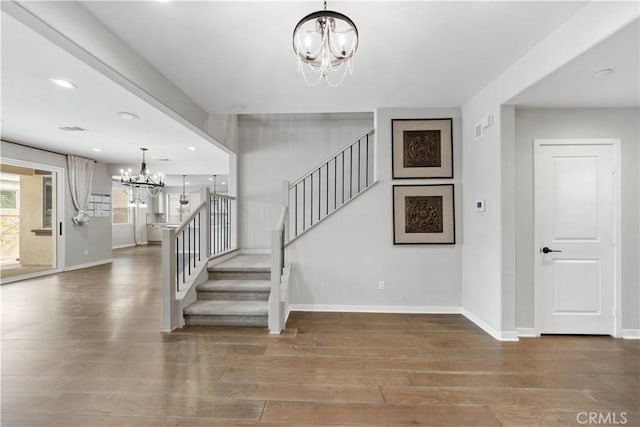 staircase featuring recessed lighting, visible vents, an inviting chandelier, wood finished floors, and baseboards