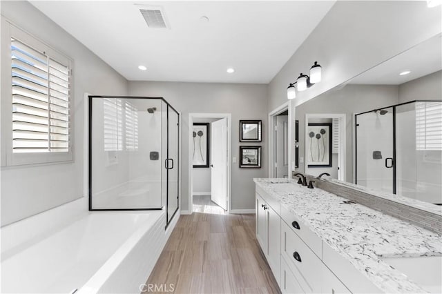 full bath featuring double vanity, a stall shower, visible vents, and wood finished floors