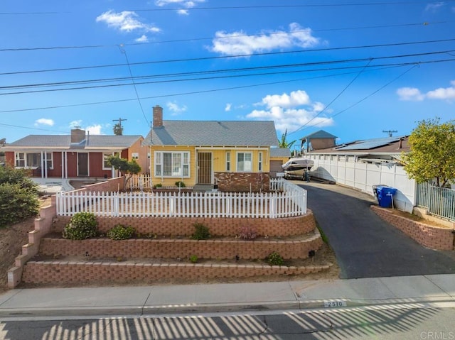 single story home featuring driveway, a fenced front yard, and a chimney