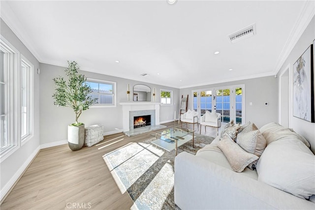 living area with french doors, crown molding, light wood finished floors, visible vents, and baseboards