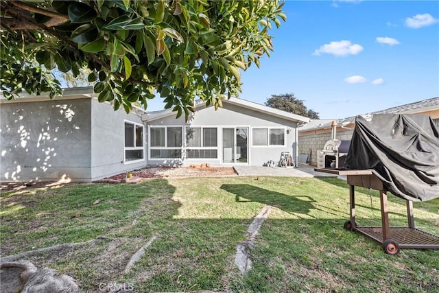 back of property with a lawn, a sunroom, fence, a patio area, and stucco siding