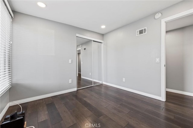 unfurnished bedroom featuring baseboards, visible vents, and wood finished floors