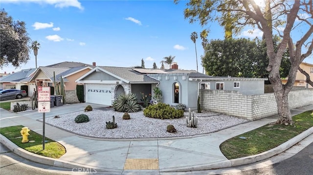 view of front of home with a garage, concrete driveway, fence, and stucco siding