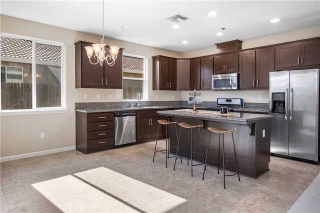 4907 Durant Way, Merced, CA 95348 - kitchen featuring a breakfast bar area, visible vents, appliances with stainless steel finishes, dark brown cabinets, and an inviting chandelier