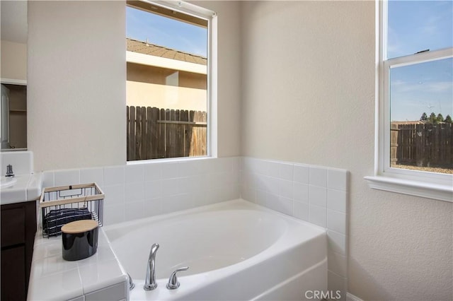 4907 Durant Way, Merced, CA 95348 - bathroom featuring a textured wall, a wealth of natural light, a garden tub, and vanity