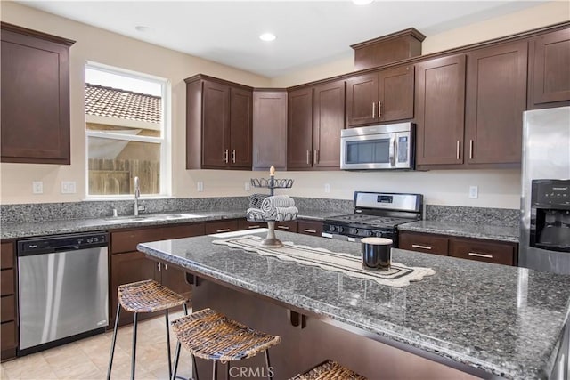 4907 Durant Way, Merced, CA 95348 - kitchen with dark brown cabinetry, a breakfast bar, dark stone counters, a sink, and stainless steel appliances