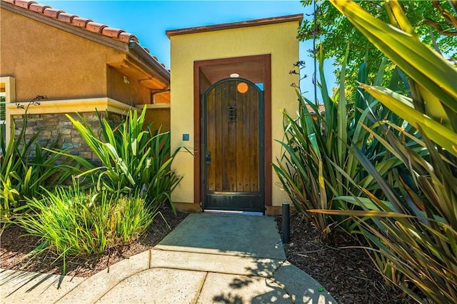 doorway to property with a tiled roof and stucco siding