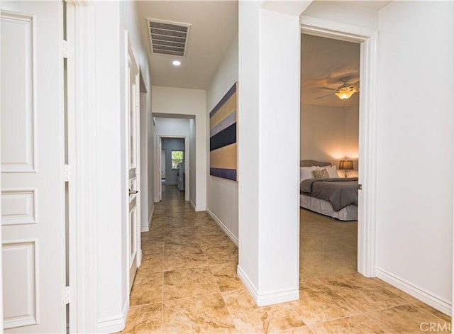 hallway with light tile patterned flooring, visible vents, and baseboards