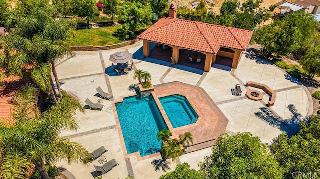 view of swimming pool featuring exterior fireplace, a patio area, and a hot tub