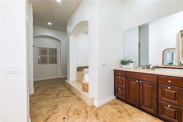 bathroom featuring a bath, recessed lighting, vanity, and baseboards