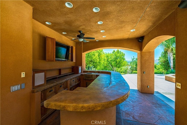 view of patio / terrace featuring a ceiling fan, an outdoor kitchen, and a sink