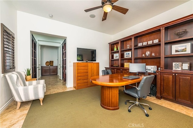 office space with light tile patterned floors, baseboards, and a ceiling fan