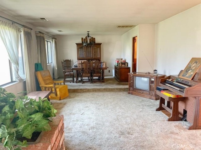 living area featuring a wealth of natural light, carpet flooring, and visible vents