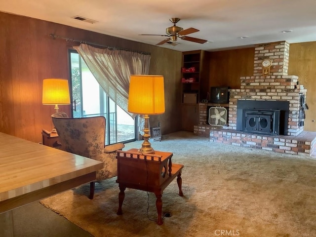 living area with wooden walls, a fireplace, visible vents, and a wealth of natural light