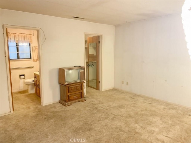 unfurnished bedroom featuring visible vents, connected bathroom, light colored carpet, a spacious closet, and a closet