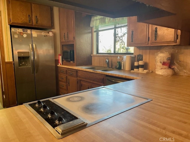 kitchen with brown cabinets, a sink, stainless steel appliances, and light countertops