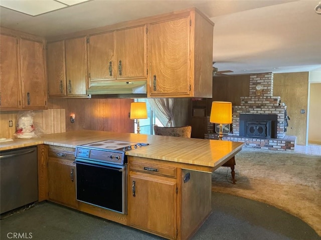 kitchen featuring under cabinet range hood, light countertops, a brick fireplace, electric range oven, and dishwasher