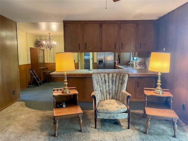 living area featuring wainscoting, carpet, wooden walls, and an inviting chandelier