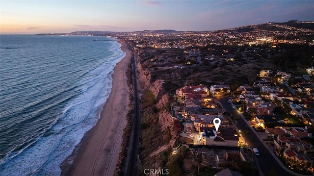 aerial view at dusk featuring a beach view and a water view