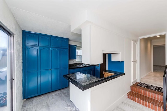 kitchen with a peninsula, tile counters, and blue cabinets