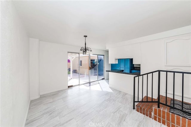 spare room with a chandelier and baseboards