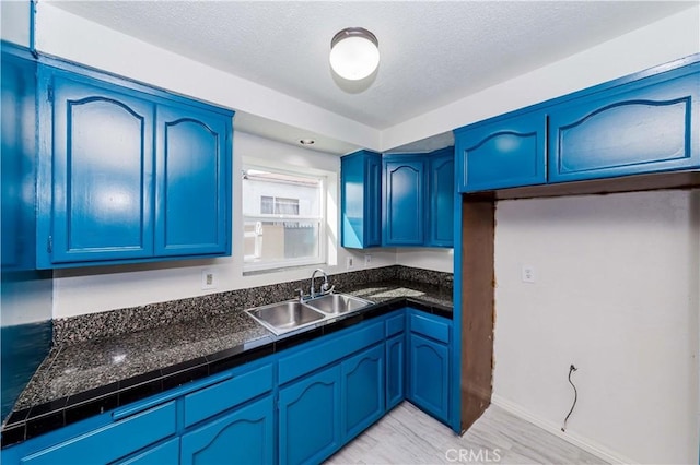 kitchen featuring blue cabinetry, a textured ceiling, and a sink